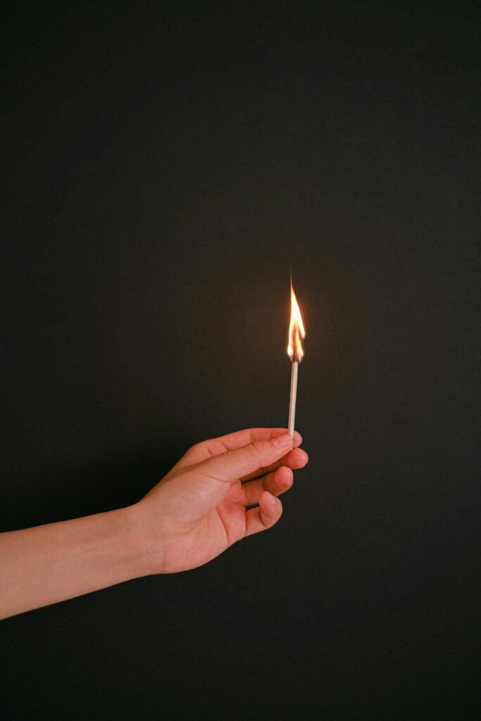 Person Holding Lighted Match Stick