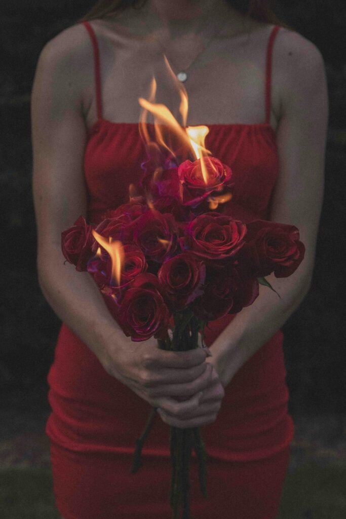 Woman in a Red Dress Holding a Bouquet of Burning Roses