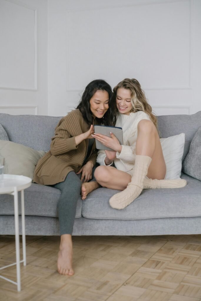 Women Looking at a Digital Tablet while Sitting on Sofa